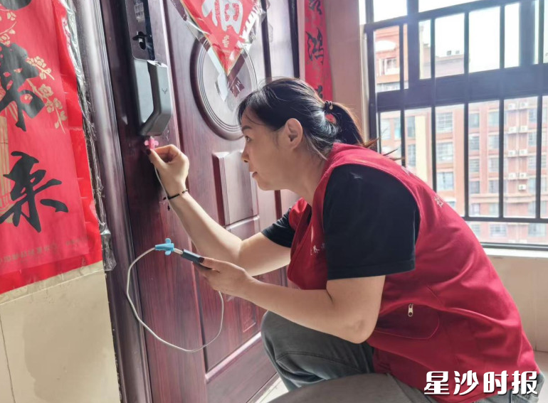 志愿者孟红云用充电宝给智能锁充电,为居民打开家门。均为街道供图 志愿者孟红云用充电宝给智能锁充电,为居民打开家门。均为街道供图