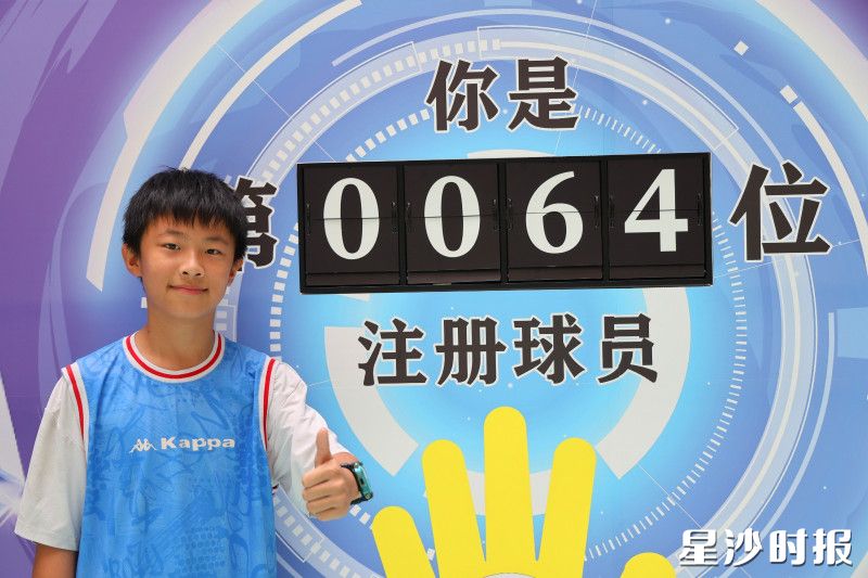 长沙华夏学校开学日设置“湘超”打卡点位，学生在“第 0064 位注册球员”展板前留影，感受体育带来的乐趣。